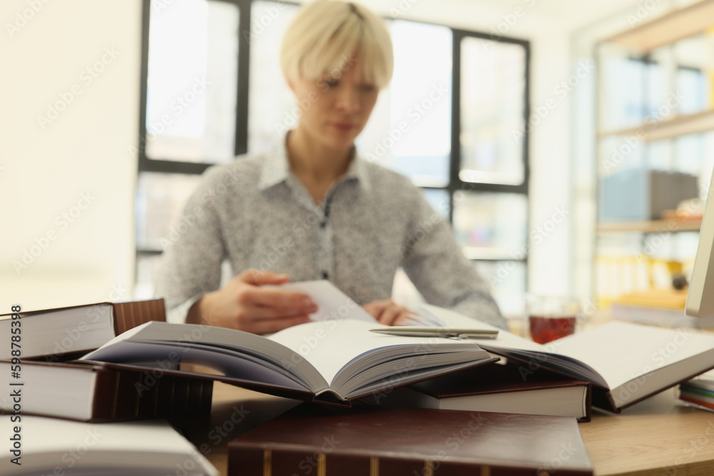 Female employee reads books to find information for research Female employee reads books to find information for research