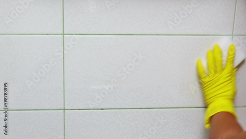 Woman hand in yellow household gloves spray cleanser on white melanin sponge on wall and rag then wipe closeup. Housewife carry out wet cleaning. Clean home, antibacterial and anti Generative AI