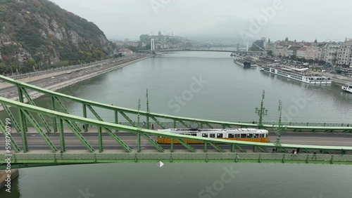 Aerial view of Budapest Szabadsag hid (Liberty Bridge or Freedom Bridge), connects Buda and Pest across the River Danube. A tram circulates within historic city along iconic bridge