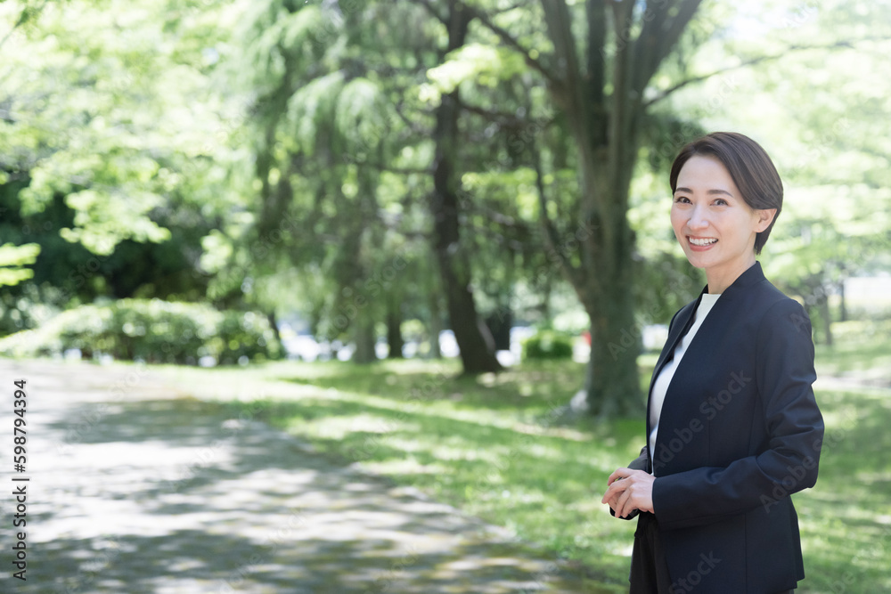 逆光の中スーツを着たスマホで話す女性 ビジネスの転職・採用・女性起用などに コピースペースあり 逆光の中スーツを着たスマホで話す女性 ビジネスの転職・採用・女性起用などに コピースペースあり