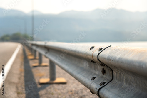 Roadside metal rail barrier structure which is installed on side of the road for protected the car accident. Transportation safety equipment object, selective focus.