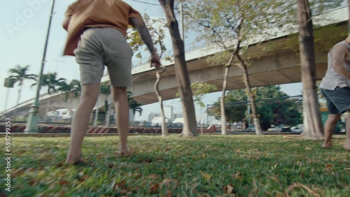 Two professional parkour athletes performing side flips synchronically, training together outdoors in the park on summer day. Slow motion, zoom shot photo