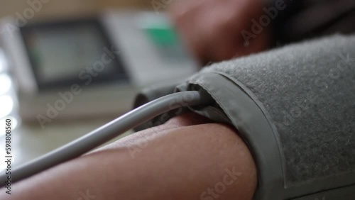 Close-up of blood pressure monitor inflating. Blood pressure gauge on the arm of the elderly woman. Using digital tonometer machine at home. Healthcare, disease treatment concept.
