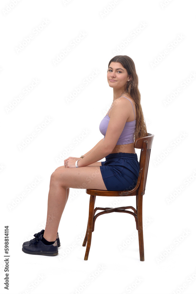 side view of a young girl sitting on chair looking at camera on white background side view of a young girl sitting on chair looking at camera on white background