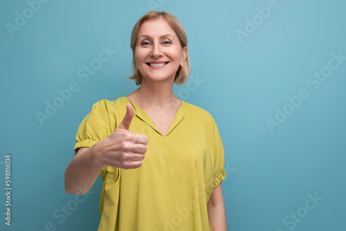 confident middle aged blond woman in casual look on blue background with copyspace