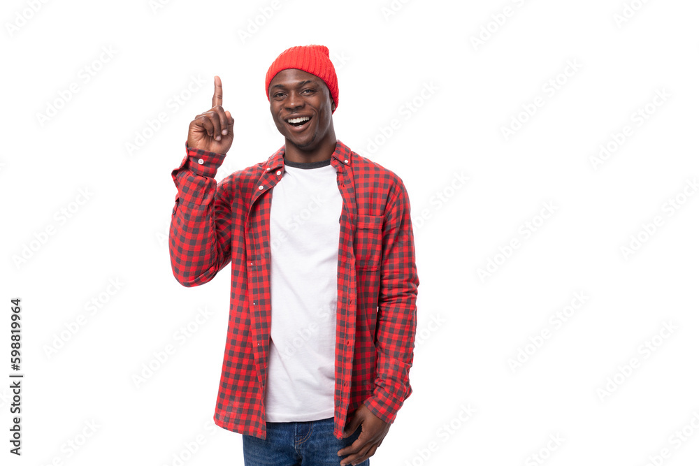 smart cute 30s black american man dressed in red shirt and cap communicates idea on white studio background with copy space smart cute 30s black american man dressed in red shirt and cap communicates idea on white studio background with copy space