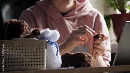 A young woman's hands knit with needles. A favourite hobby, handicraft.