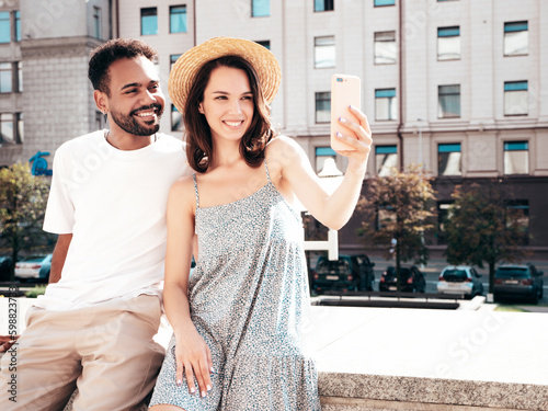 Smiling beautiful woman and her handsome boyfriend. Woman in casual summer clothes. Happy cheerful family. Female having fun. Sexy couple posing in the street at sunny day. In hat, taking selfie
