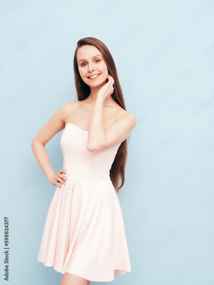 Portrait of young winsome woman in romantic attire pretty smiling on blue background. Slim female in pure pink dress posing in studio. Cheerful model. Isolated. Long hair Portrait of young winsome woman in romantic attire pretty smiling on blue background. Slim female in pure pink dress posing in studio. Cheerful model. Isolated. Long hair