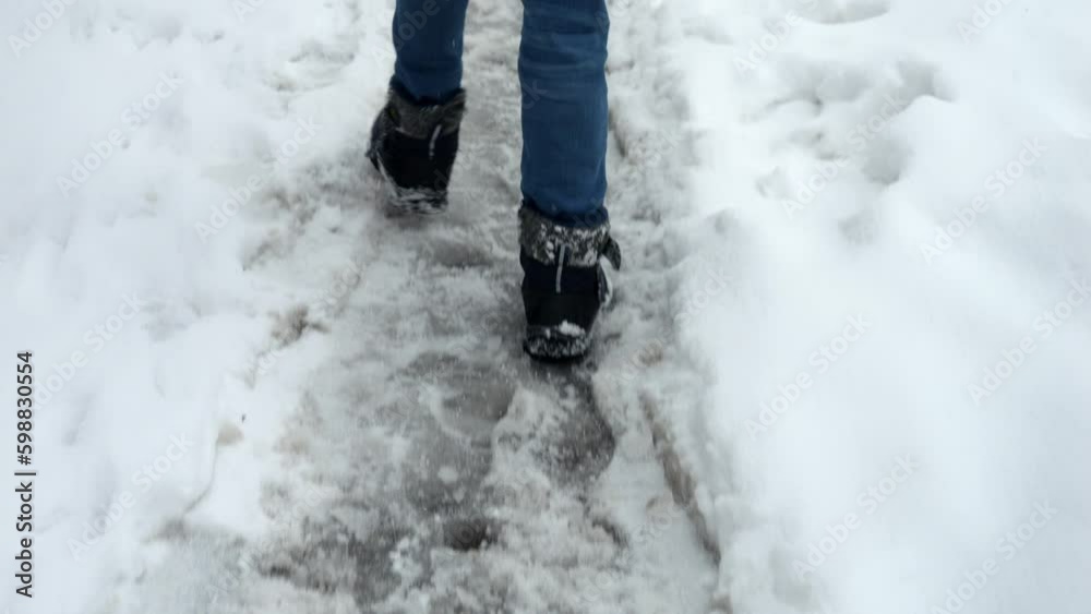 Closeup of child's feet in snow boots walking on road covered with snow after storm. Closeup of child's feet in snow boots walking on road covered with snow after storm.