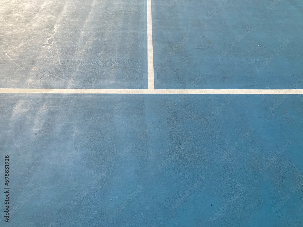 empty blue tennis court and white lines on it in natural bright daylight