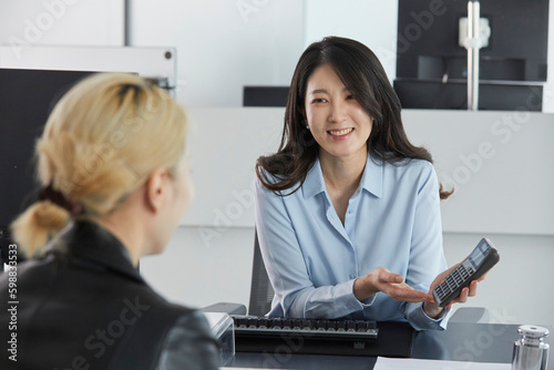 은행 직원이 보여주는 계산기 금액을 확인하는 고객 photo