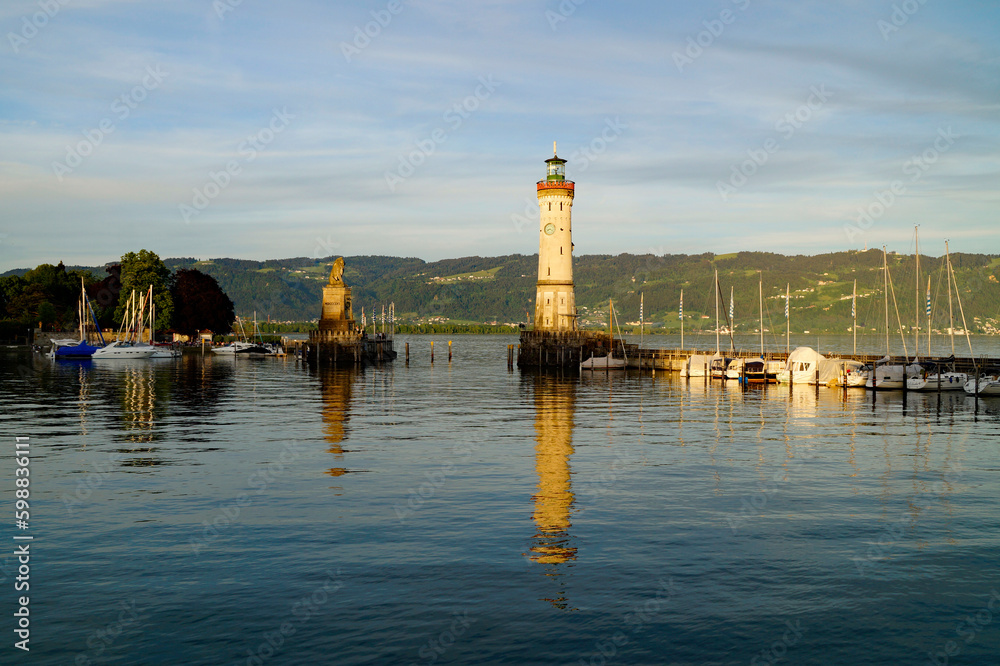 beautiful sun-drenched harbour of Lindau island with beacon and the sculpture of the Bavarian Lion on lake Constance (Bodensee) with the Alps in the background, Germany on fine sunny spring evening