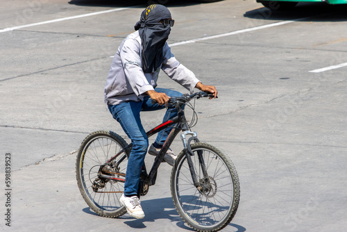 A man with hidden face ride on a bicycle at sunny street, Thailand.