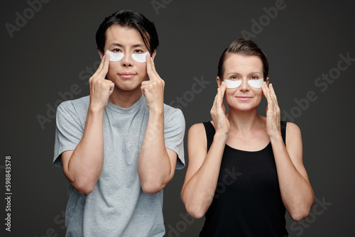 Positive man and woman applying endereye patches and looking at camera