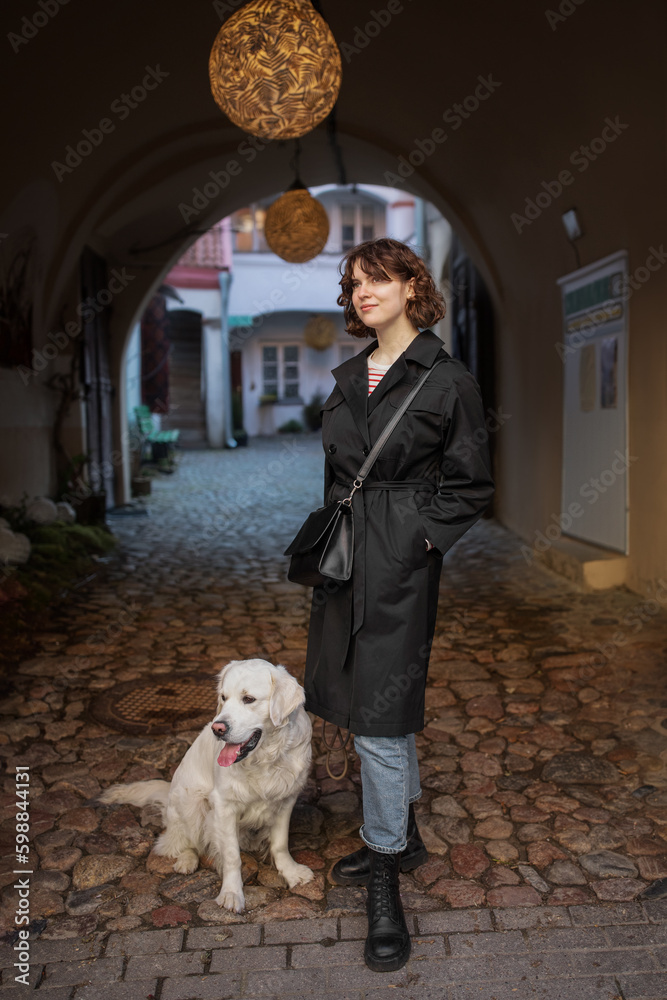 Cute funny girl portrait with her golden dog on street
