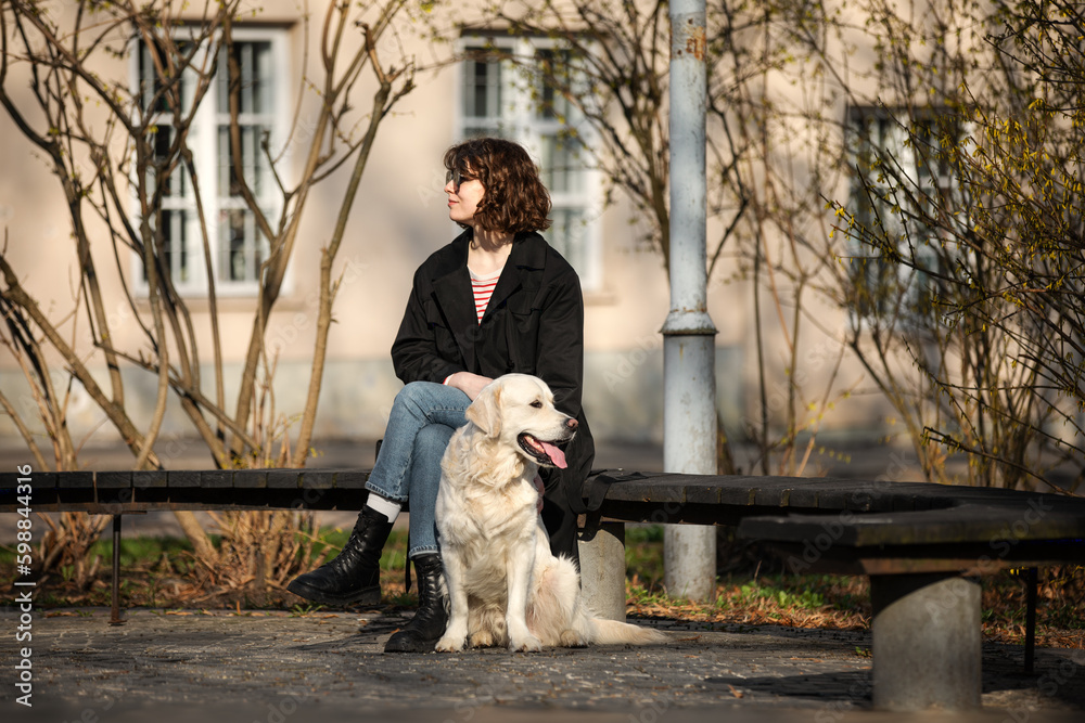 Cute funny girl portrait with her golden dog on street