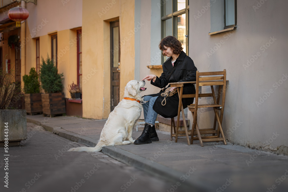 Cute funny girl portrait with her golden dog on street