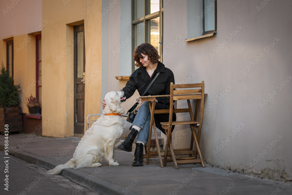 Cute funny girl portrait with her golden dog on street