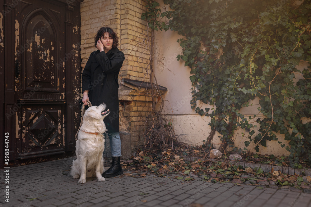 Cute funny girl portrait with her golden dog on street