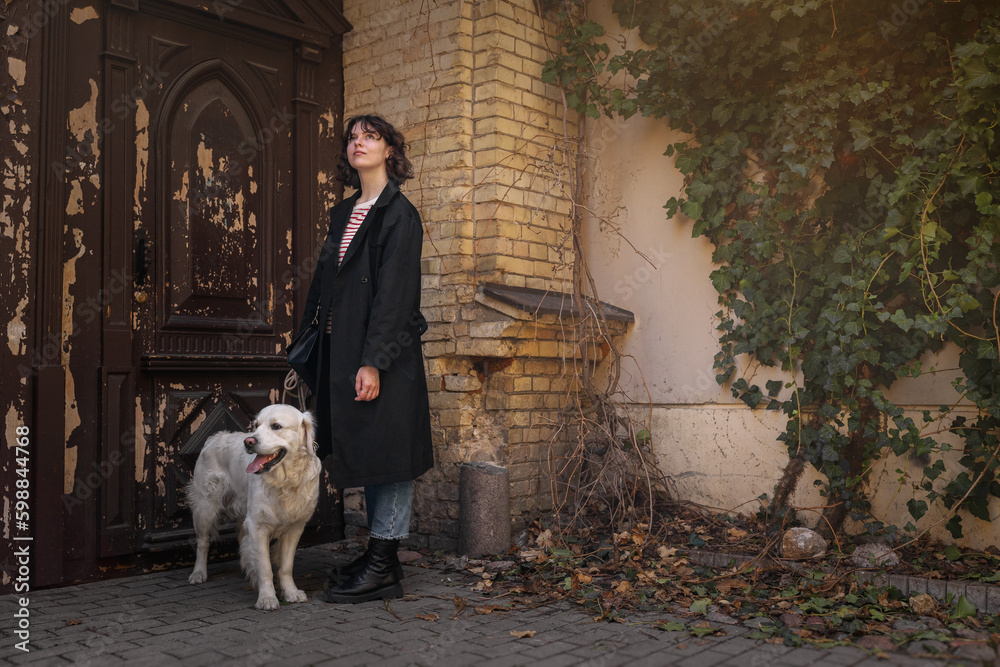 Cute funny girl portrait with her golden dog on street