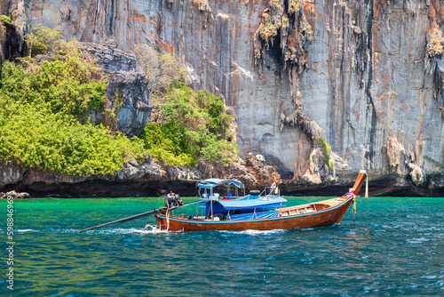 Old traditional Thai motorboat made of wood for fishing and tourists on excursions in the Andaman Sea near Phi Phi Leh island in clear turquoise water under a blue sky. Travel and vacation in phuket.