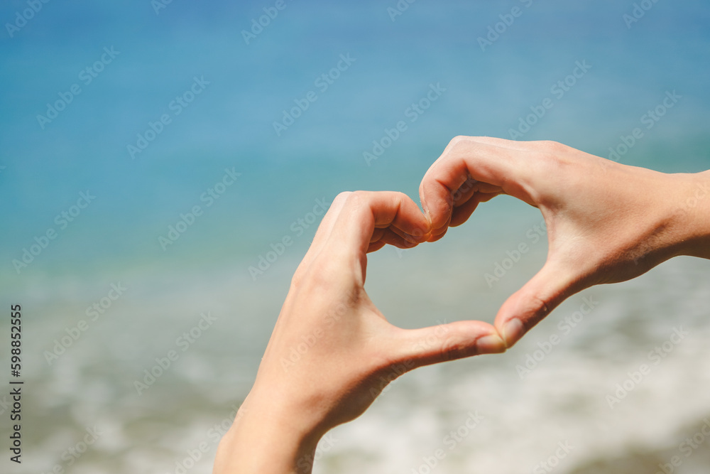 Girl hand in heart form love with ocean sunset background