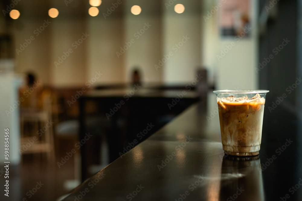 A glass of iced coffee sits on a table in front of a bar.