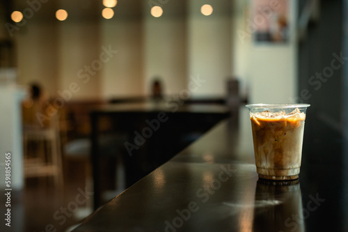 A glass of iced coffee sits on a table in front of a bar.