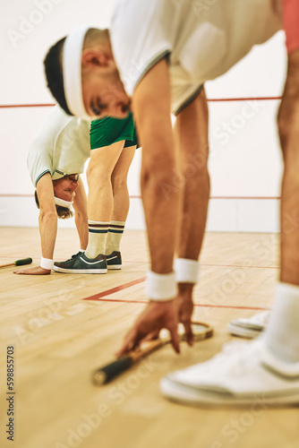 The perfect sport to get your body fit. two young men stretching before playing a game of squash.