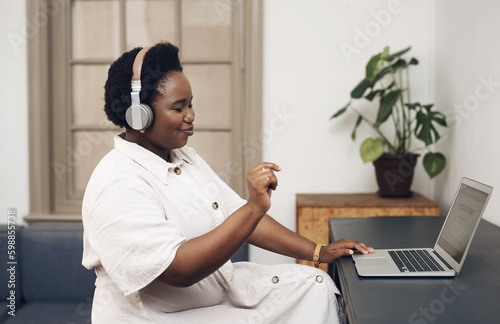 Grooving to the beat of success. a young businesswoman using headphones and a laptop in an office.