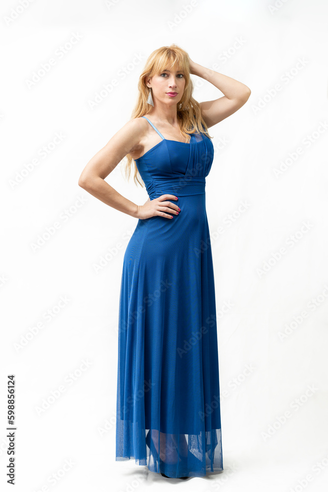 portrait of an attractive middle-aged blonde Caucasian girl with one hand on her hips and one on her head, dressed in a pretty blue party dress.