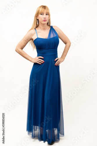 beautiful middle-aged blonde Caucasian woman with her hands on her hips and a serious look, dressed in a beautiful blue party dress.