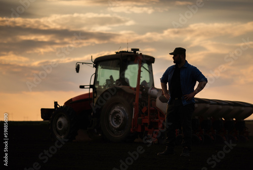  Satisfied tractor driver after work on agricultural field stands next to tractor. © Dusan Kostic