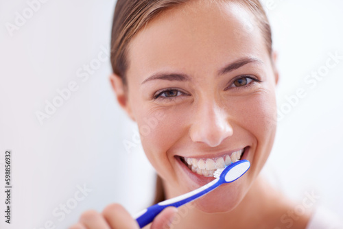 Young woman, portrait and brushing teeth in bathroom with smile, health or self care for hygiene, wellness and routine. Girl, toothbrush and happiness for cleaning, healthy mouth and start morning