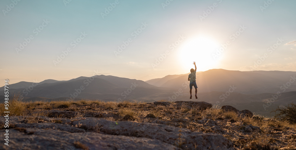 silhouette of a jumping man against the background of the sky and sunset in the mountains