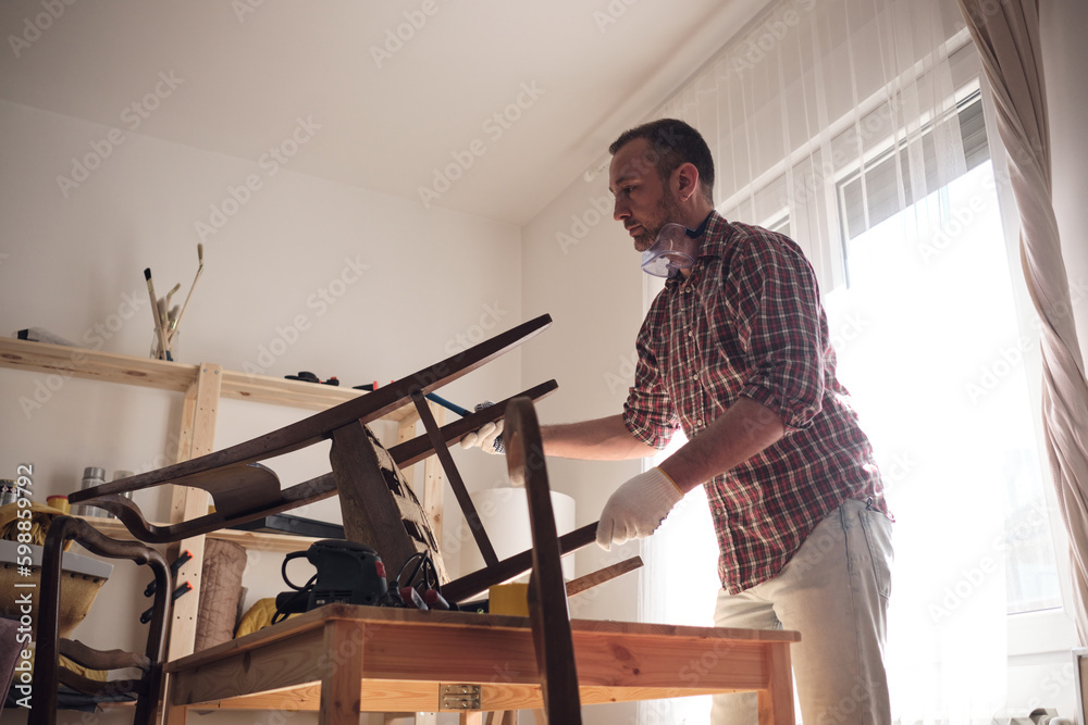 Man working in a small home workshop for furniture repairing and restoration.
