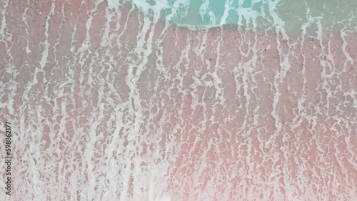 Aerial top view of tropical pink sand beach and crashing waves. Beautiful sea waves. Pink sand and amazing sea. Summer sunset seascape. Atlantic Ocean beach sunsets. Fantastic natural Generative AI
