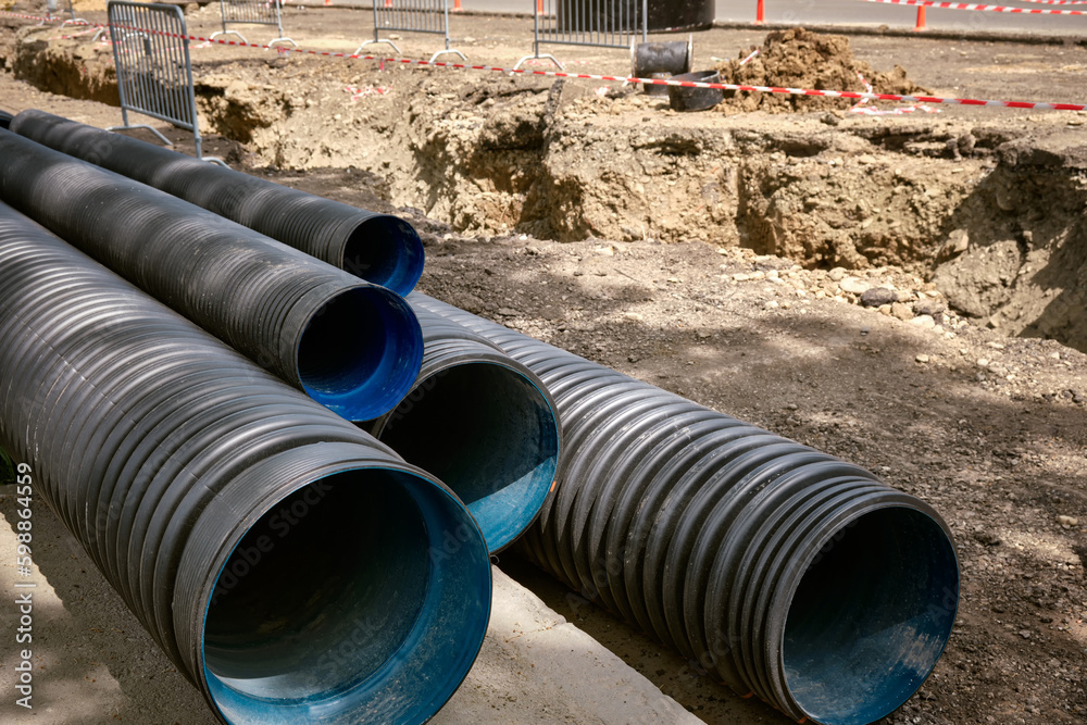 Large plastic corrugated pipes for water supply lie on the street in the city.