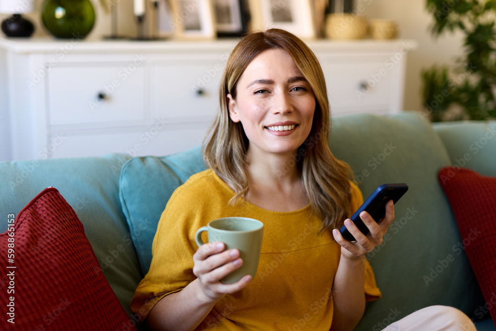 Woman using smartphone while drinking coffee at her home in the morning Woman using smartphone while drinking coffee at her home in the morning