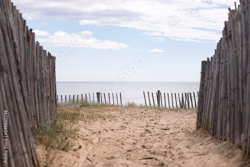 Entrance to the beach with wooden fence, view on the sea and horizon. Footpath to empty beach.  Beach holidays background. © MindestensM