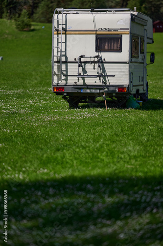 Obraz na płótnie old school white camper parked on the grass by the lake. A vintage house on wheels in a sunny aura. w salonie