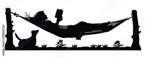 Relaxed silhouette of woman reading book lying hanging from tree with dog.