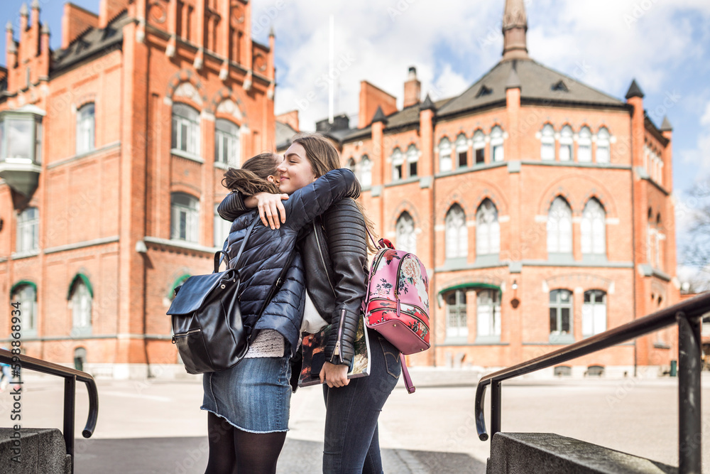 Female friends hugging in school courtyard Female friends hugging in school courtyard