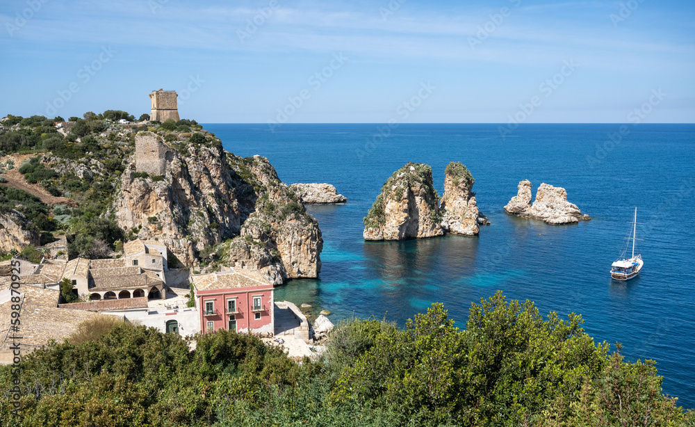 The pink building of the former tuna catcher Tonnara di Scopello is located on the blue tyrrhenian Mediterranean Sea in a picturesque bay between rough rocks