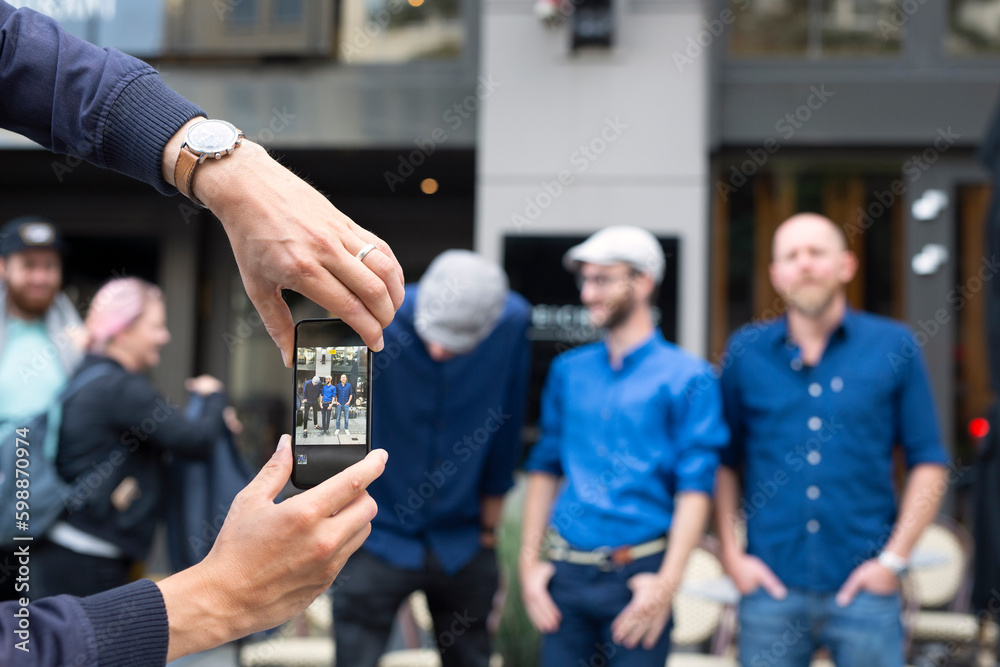 Close-up of man photographing friends with smart phone Close-up of man photographing friends with smart phone
