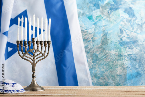 Happy Hanukkah. Hanukkah old Menorah against background of the Israeli flag with sunlight or bokeh on white wooden background. Religion image of jewish holiday Hanukkah background.