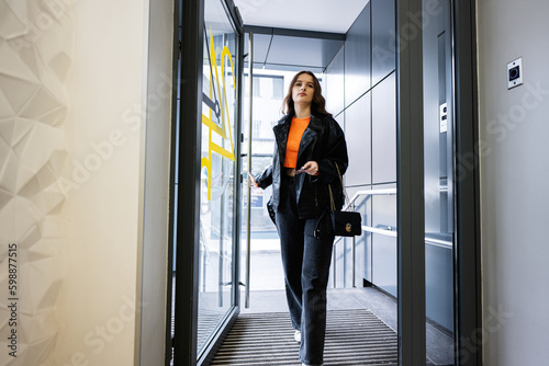 Young lady enters institution firm department, opening the door.