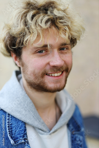 Close-up portrait of smiling attractive young curly blonde man with beard.