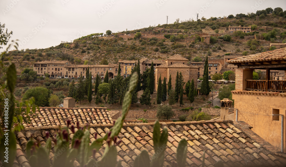 Panoramic view of the roofs of the buildings and small brick houses of the touristy medieval village of Alquezar, located on a hill surrounded by mountains in Aragon, Huesca.